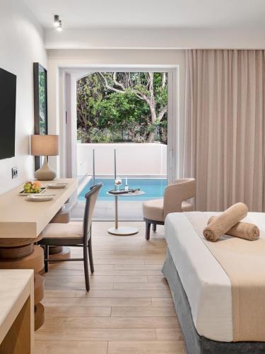 a hotel room with two beds and a table and chairs at Creta Royal - Adults Only in Skaleta