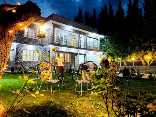 a house with a table and chairs in the yard at night at Paradiso Lodge Skardu in Skardu