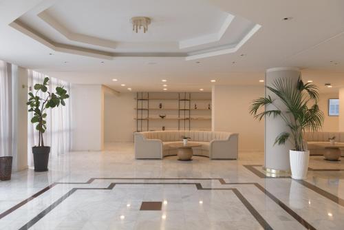 a lobby with a waiting area with couches and plants at Creta Royal - Adults Only in Skaleta