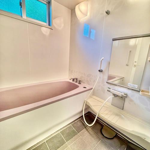 a bathroom with a tub and a sink at ペンション波 in Ufugumui