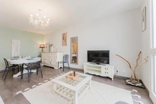 a living room with a table and a tv at Appartement Lumineux 2 chambres avec parking in La Madeleine