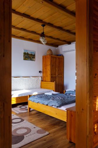 a bedroom with two beds and a wooden ceiling at Rózsa-Domb Vendégház in Golop