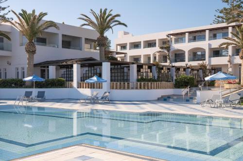 a swimming pool in front of a hotel with palm trees at Creta Royal - Adults Only in Skaleta
