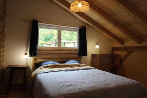 a bedroom with a large bed and a window at Gîte tout confort Les Champs de la Goutte à Moussey, au calme au cœur des Vosges in Moussey