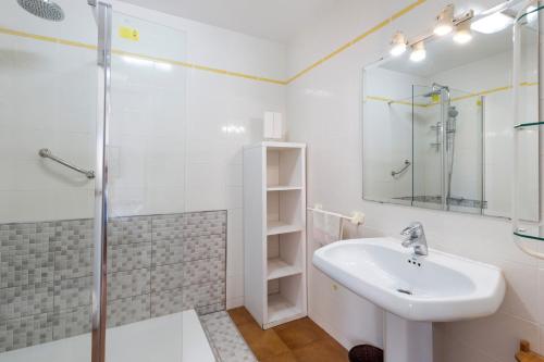 Un baño blanco con lavabo y ducha. en La Gola, en La Manga del Mar Menor