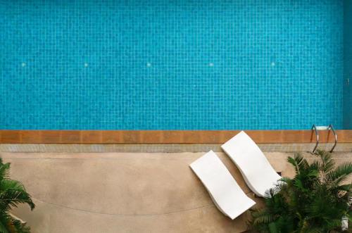two white chairs sitting next to a swimming pool at Spacious and Renovated 1-Bedroom 100m to Nana BTS - 55 sqm in Bangkok