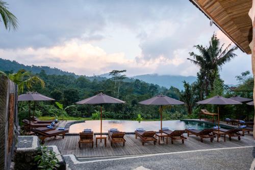 a pool at a resort with chairs and umbrellas at Cassowary Villas Sidemen by AGATA in Sidemen