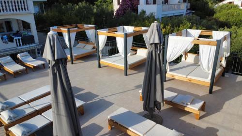 a group of lounge chairs and umbrellas on a patio at Villa Rajski Dvor in Bol