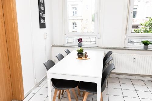 a white table and chairs in a room with windows at CosyHomes24 - centrally with balcony and garage - IL01b in Iserlohn