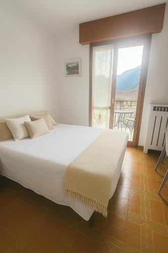 a white bed in a room with a large window at CASA STAVELLO in Sernio