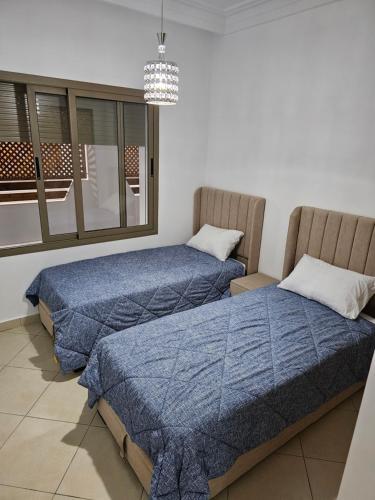a bedroom with two beds and a window at Résidences Nawal in Asilah