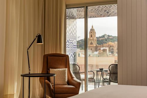 a hotel room with a bed and a chair and a window at H10 Croma Málaga in Málaga