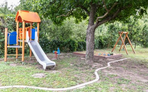 a playground with a slide and a tree at Park Apartman in Sarród