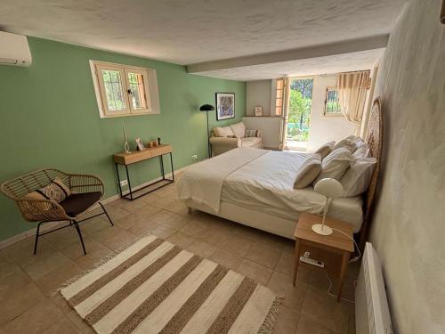 een slaapkamer met een bed, een stoel en een raam bij Les Bosquets in Lorgues