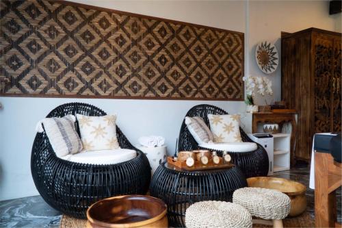 two wicker chairs and a table in a room at Casa Maddu in Tegalalang