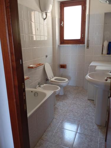 a bathroom with a toilet and a tub and a sink at PM 135 Corso Umberto Guest House in Cuglieri
