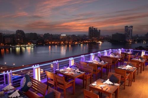 a row of tables on a balcony with a view of the water at Novotel Cairo El Borg in Cairo