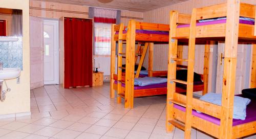 a room with three bunk beds and a bathroom at Hostel Waldhaus am Ferienpark Gruppenhaus in Mirow