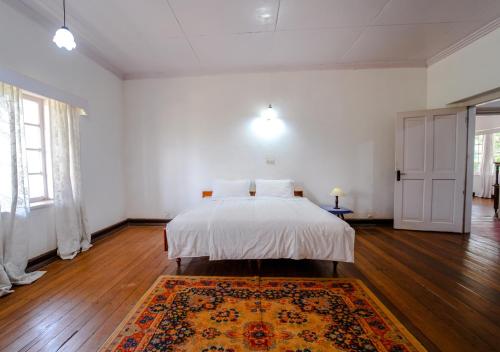 a white bedroom with a bed and a rug at Arivikad Tea Bungalow Munnar By VOYE HOMES in Munnar