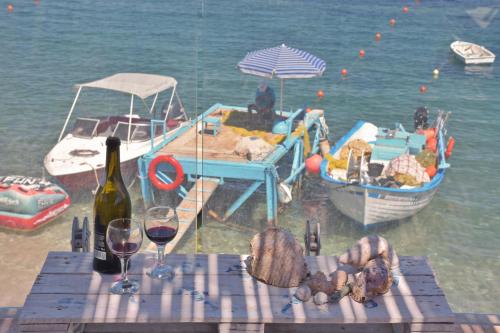 a table with wine glasses and a boat on the water at Mpitzarakis Studio On the Beach in Agia Pelagia
