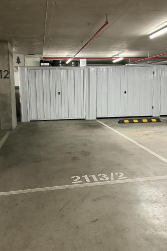 a garage with white doors and a parking lot at Modern Minimalist Apartment in Belconnen