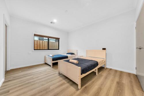 Wyndham ValeにあるWyndham Vale Retreat- Disability Friendly Accommodation- 4 Bedroom Holiday Homeの白い壁とウッドフロアの客室で、ベッド2台が備わります。