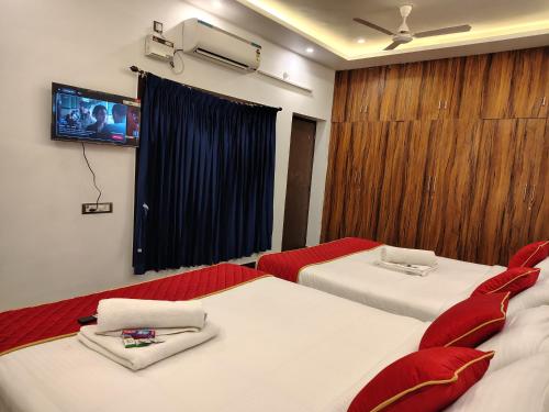 a hotel room with two beds and a flat screen tv at THE VILLA Pondicherry in Puducherry