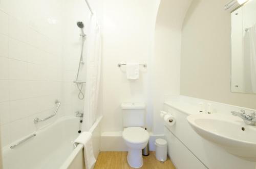 a white bathroom with a toilet and a sink at The Corner House Hotel in Taunton