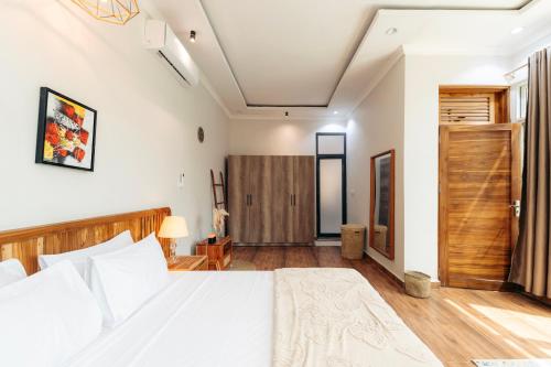a bedroom with a white bed and a wooden door at Twin Villa Zulia by Zanzibar Stays - Private Pool Villa Jambiani in Jambiani