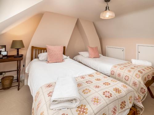 deux lits dans une chambre mansardée avec des draps roses et blancs dans l'établissement Charming 2 Bed Cottage in the Heart of Adderbury Pass the Keys, à Adderbury