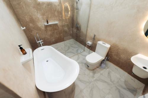 a bathroom with a toilet and a sink at Twin Villa Zulia by Zanzibar Stays - Private Pool Villa Jambiani in Jambiani