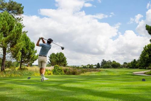 a man swinging a golf club on a golf course at La Paris Estate in Franschhoek