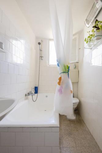 a bathroom with a tub and a toilet with a shower curtain at Charming 2 BR Apt By The Foot Of The Bahai Temple in Haifa