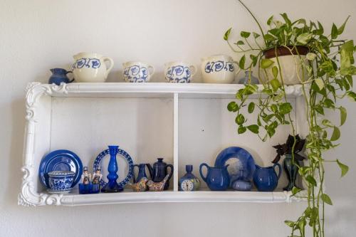 a shelf with blue and white dishes and a plant at Charming 2 BR Apt By The Foot Of The Bahai Temple in Haifa