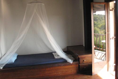 een slaapkamer met een bed met een gordijn en een balkon bij Traditional Stonehouse in Potistika