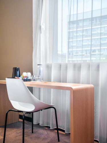 a white chair sitting in front of a wooden desk at Hotel Ibis Krakow Centrum in Kraków