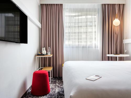 a hotel room with a white bed and a red chair at Hotel Ibis Krakow Centrum in Kraków
