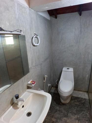 a bathroom with a white toilet and a sink at Wilpattu Nature Resort in Murandanveli