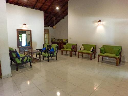 a waiting room with green chairs and tables at Wilpattu Nature Resort in Murandanveli