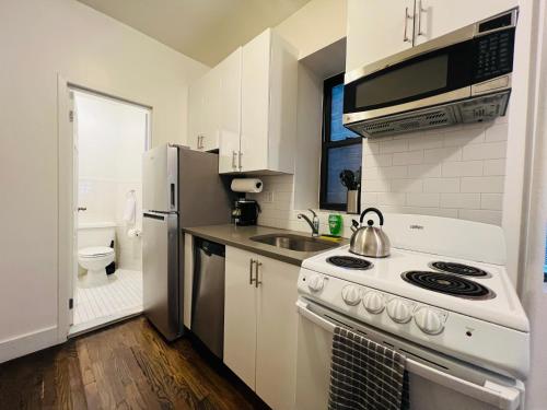 a white kitchen with a stove and a refrigerator at The Manhattan on 48th in New York