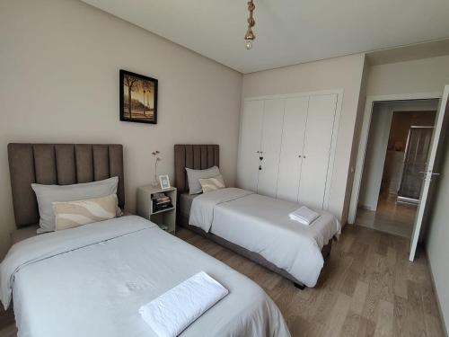 a bedroom with two beds and a mirror at Chambre très propre avec salle de bain privée - 5 min airport casablanca in Nouaseur