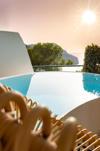 a wicker chair sitting next to a swimming pool at Hacienda Na Xamena, Ibiza in Na Xamena
