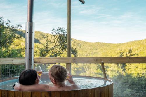 two people in a hot tub with a glass of wine at AfriCamps Addo in Swanepoelskraal