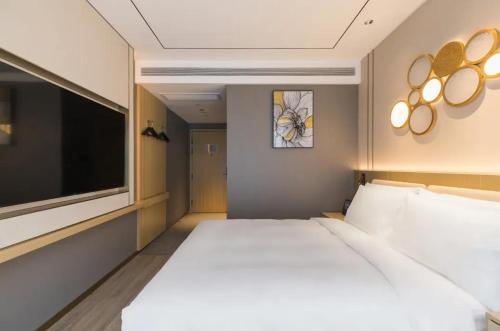a bedroom with a large bed and a flat screen tv at Orange Hotel Beijing Zhongguancun Renmin University in Beijing