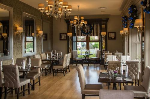 a restaurant with tables and chairs and a chandelier at Errigal Country House Hotel in Cootehill