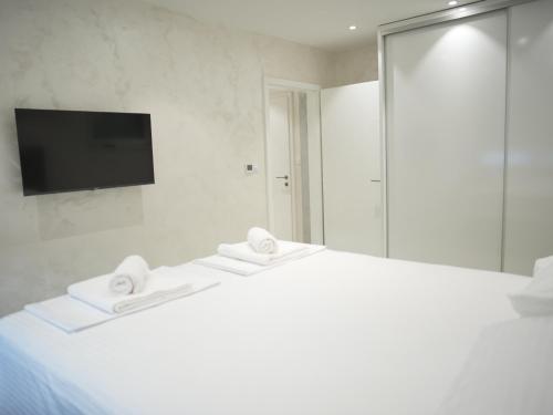 a bedroom with a white bed with a television on the wall at Apartment Elenor in Mostar