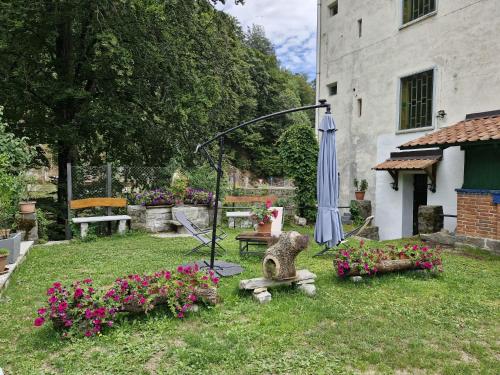 a garden with an umbrella and a bench and flowers at Ponte Fontana in Campiglia Cervo