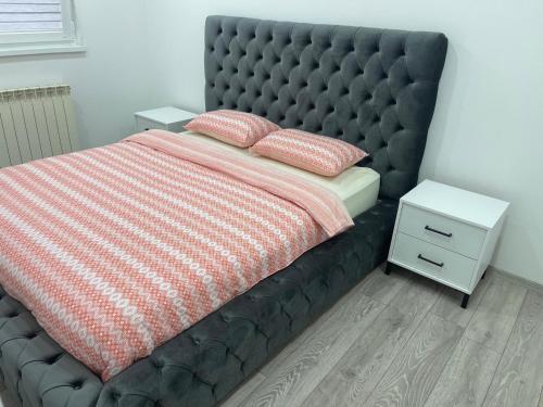 a bed with a black padded headboard and a night stand at Apartment Vogošća centre in Vogošća
