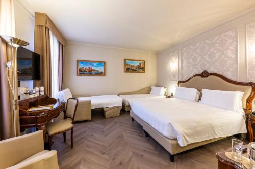 a hotel room with two beds and a desk at Hotel Colombina in Venice