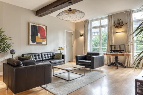 a living room with a leather couch and a table at L'Astrolabe - superbe appartement vue Cathédrale in Rouen
